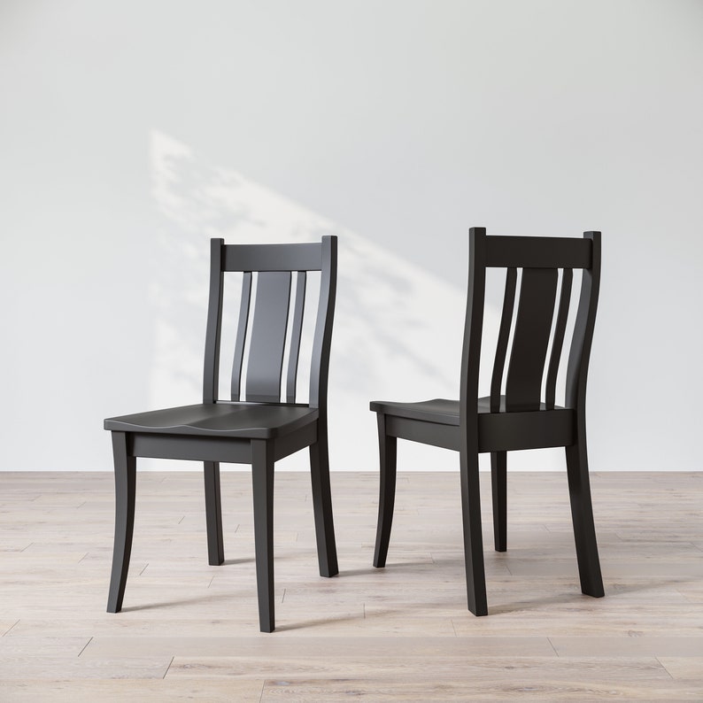 May include: Two black wooden chairs with a simple, classic design. The chairs have a slatted back and a curved seat.