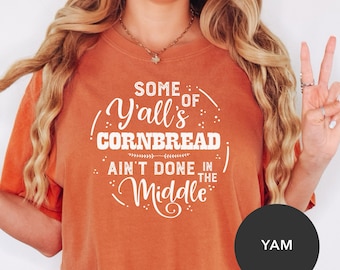 May include: Orange t-shirt with white text that reads "Some of Y'all's Cornbread Ain't Done in the Middle".