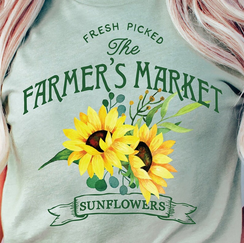 May include: A light blue t-shirt with the text "Fresh Picked The Farmer's Market Sunflowers" in green lettering. The text is surrounded by two yellow sunflowers with green leaves.