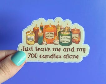 May include: A sticker featuring a collection of lit candles in various colors and sizes. The text on the sticker reads "Just leave me and my 700 candles alone."