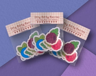 Puede incluir: Una bolsa de plástico transparente llena de pegatinas con lindas ilustraciones de dibujos animados de frambuesas y arándanos. Las pegatinas están etiquetadas como "Itty Bitty Berries cute tiny kiss cut stickers".