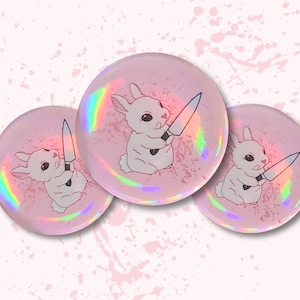 May include: Three pink holographic buttons with a white rabbit holding a knife. Each button has a different pose of the rabbit.