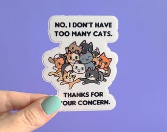 Puede incluir: Pegatina blanca con una ilustración de dibujos animados de una pila de gatos y el texto "NO, I DON'T HAVE TOO MANY CATS. THANKS FOR OUR CONCERN."