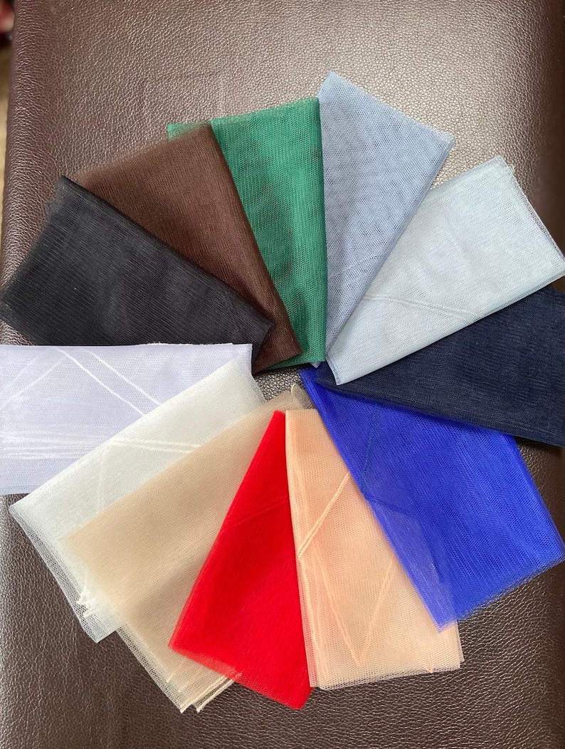 May include: Assortment of 10 different colors of tulle fabric swatches. The colors are black, brown, green, light blue, white, beige, red, peach, blue, and navy.