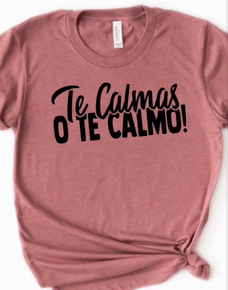 Puede incluir: Una camiseta color malva con el texto "Te Calmas o Te Calmo!" impreso en negro.