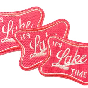 May include: Three pink fabric patches with white embroidered text that reads "IT'S Lake TIME". The patches have a retro diner-style design with a white border.