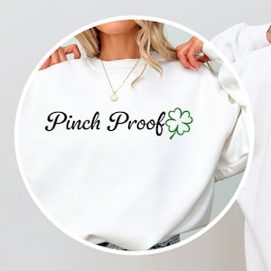 May include: White sweatshirt with the text "Pinch Proof" in black cursive font and a green four-leaf clover graphic.