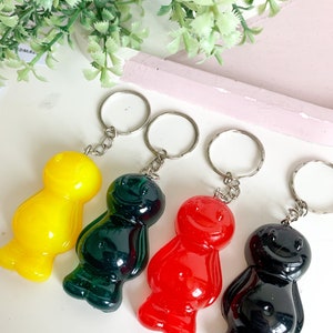 May include: Four gummy bear shaped keychains in yellow, green, red, and black. Each keychain has a silver metal ring.