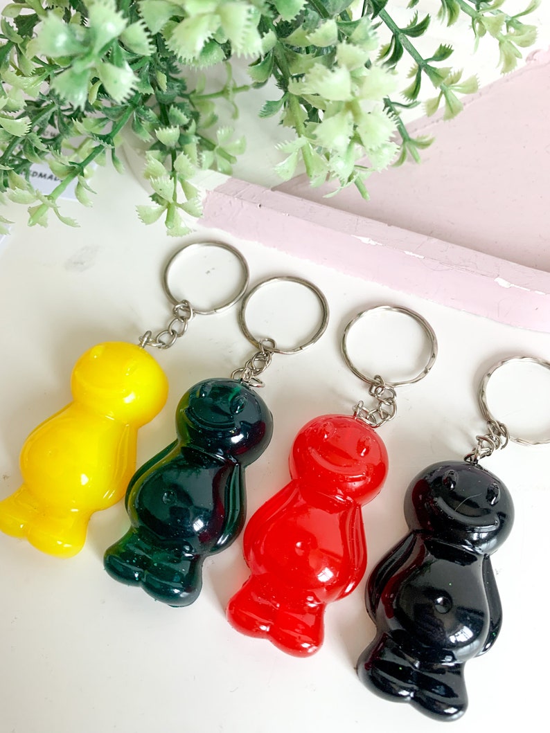 May include: Four gummy bear shaped keychains in yellow, green, red, and black. Each keychain has a silver metal ring.