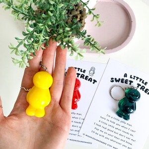 May include: Two keychains featuring a yellow and a green jelly bean shaped charm. The charms are attached to silver key rings. The keychains are displayed on cards with the text "A Little Sweet Treat" and "A Little Treat".