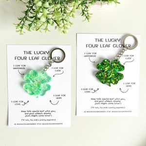 May include: Two four-leaf clover keychains. One is light green, the other is glittery green. Each keychain has a metal ring and a card with text: "THE LUCKY FOUR LEAF CLOVER" and "1 LEAF FOR HAPPINESS, LUCK, HOPE, LOVE".