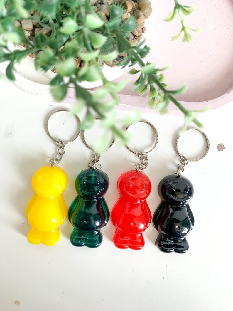 May include: Four jelly bean shaped keychains in yellow, green, red, and black.