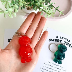 May include: A red and green jelly bean keychain with a silver chain. The keychain is accompanied by a card that reads "A Little Sweet Treat" and includes a short poem about the jelly bean.