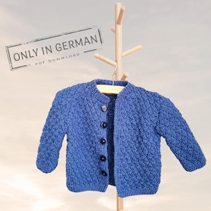 Puede incluir: Un cárdigan de punto azul para bebé con cierre de botones. El cárdigan está colgado en una percha de madera. El texto "ONLY IN GERMAN PDF DOWNLOAD" es visible en la esquina superior izquierda de la imagen.