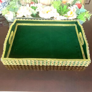 May include: A green velvet tray with a gold beaded trim. The tray is rectangular in shape and is ideal for serving or displaying items.
