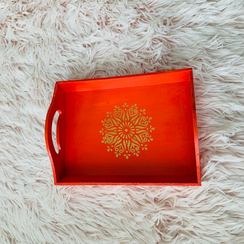 Puede incluir: Bandeja de servir de madera naranja con un dise&ntilde;o de mandala dorado.