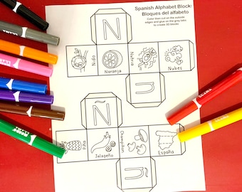 May include: A white sheet with a Spanish alphabet block design, featuring illustrations and Spanish words. The sheet includes the text "Spanish Alphabet Block! Bloques del alfabeto". Various colored markers surround the sheet.