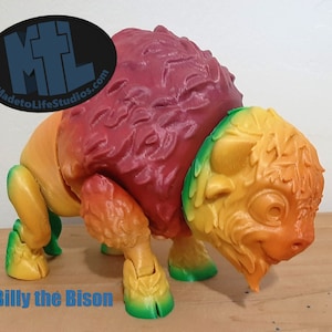 May include: A colorful, 3D printed bison figurine with a gradient of red, orange, yellow, and green. The figurine is posed standing with its head lowered. The figurine is labeled "Billy the Bison".