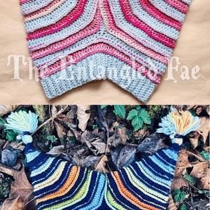 May include: Two handmade crochet shawls. The top shawl is light blue, pink, and gray with a chevron pattern. The bottom shawl is navy blue with blue, orange, and yellow stripes. Both have a pointed shape and are displayed on a neutral background.