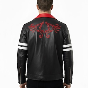 Könnte beinhalten: Schwarze Lederjacke mit rotem Kragen und rotem Stickmuster auf dem Rücken. Mit weißen Streifen auf den Ärmeln und silbernen Reißverschlüssen. Die Jacke ist im klassischen Biker-Stil gehalten.