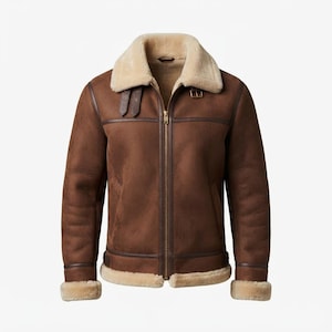 May include: A brown suede jacket featuring a cream-colored faux shearling lining and collar. The jacket includes a central gold-tone zipper, two adjustable buckle straps at the neck, and matching faux shearling trim at the cuffs and hemline.