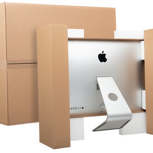 May include: A silver computer monitor with a white stand is packaged in a brown cardboard box. The monitor has an Apple logo on the back.