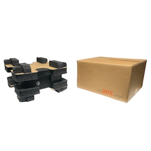 May include: A black electronic device is packaged in a cardboard box with the words "the BOX larger" printed on the side. The device is surrounded by black foam padding.