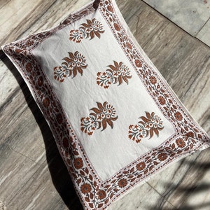 May include: A white pillowcase with a brown floral pattern. The pillowcase has a border of small brown flowers and leaves.
