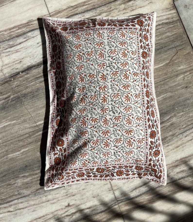 May include: A white pillowcase with a brown and gray floral pattern. The pillowcase has a border of brown and gray flowers.