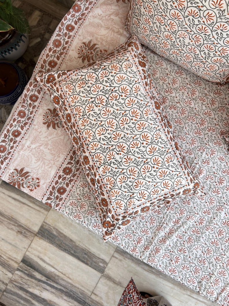 May include: A white cotton pillowcase with a floral pattern in shades of orange and gray. The pillowcase has a border of orange and gray floral print.