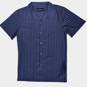 May include: Navy blue short-sleeve shirt with vertical white pinstripes. The shirt has a camp collar and a button-down front. The brand name "HOLOKAI SURF CO." is printed on the collar.