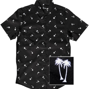 May include: Black short-sleeved button-down shirt with a white palm tree print. The shirt has a pocket on the left side and a button-up collar.