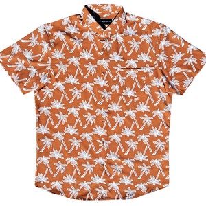 May include: A short-sleeved button-down shirt with a brown background and a white palm tree pattern.