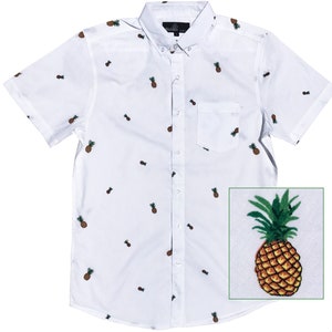 Könnte beinhalten: Weißes, kurzärmeliges Hemd mit Knöpfen und Ananas-Druck. Das Hemd hat eine Tasche auf der linken Seite.