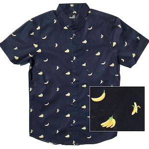 May include: Navy blue button-down shirt with a yellow banana pattern. The short-sleeved shirt features a button-down collar, a chest pocket, and a small banana print on the collar. The shirt is a casual style.