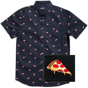 Puede incluir: Una camisa de botones de manga corta de color azul marino con un patrón repetido de rebanadas de pizza. La camisa tiene un bolsillo en el lado izquierdo y un cierre de botones. Las rebanadas de pizza son una ilustración de dibujos animados con colores rojo, amarillo y marrón.