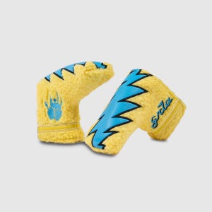 May include: Two yellow golf club head covers with blue lightning bolt designs and the word "Gola" in script. One cover has a blue paw print. The covers are made of a fuzzy material and have yellow and blue accents.