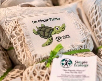 Puede incluir: Un conjunto de bolsas de malla blanca con un gráfico de tortuga verde y marrón y el texto "No Plastic Please" y "Simple Ecology." Las bolsas están atadas con una cinta verde.