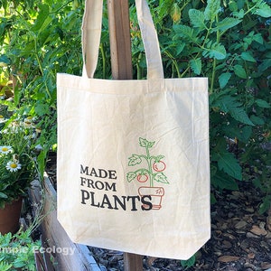 May include: A beige tote bag with a green plant and red tomatoes in a pot printed on the front. The text "MADE FROM PLANTS" is printed below the image.