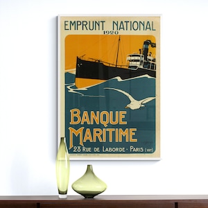 May include: A vintage poster advertising a French bank, Banque Maritime, with a black and white illustration of a ship sailing on blue water with a seagull flying overhead. The poster has a yellow background with the text "Emprunt National 1920" at the top and "28 Rue de Laborde - Paris (VIII)" at the bottom.