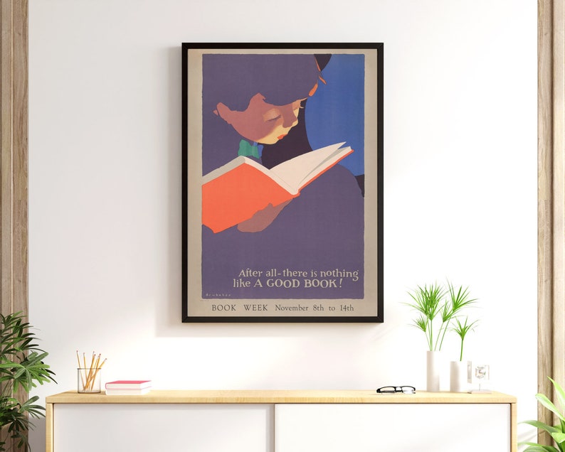 May include: A vintage poster advertising Book Week, featuring a child reading a book. The poster is in a black frame and has a purple, blue, and orange color scheme. The text on the poster reads "After all-there is nothing like A GOOD BOOK! BOOK WEEK November 8th to 14th."