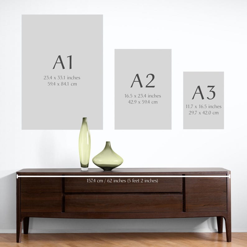 May include: Three different sizes of paper, labeled A1, A2, and A3, with their dimensions in inches and centimeters. The paper is displayed on a white wall above a dark brown wooden dresser with three drawers. The dresser is 62 inches long.