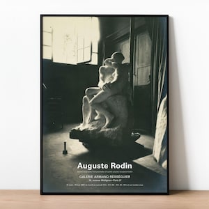 May include: Black and white framed print featuring Auguste Rodin's sculpture, "The Kiss." The artwork depicts two figures embracing. The print includes the artist's name and gallery information. The image is set in a room with a window and a door.