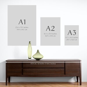 May include: A white wall with three different sized frames labeled A1, A2, and A3. The frames are hanging on the wall. The measurements of each frame are listed in inches and centimeters. Below the frames is a dark brown wooden dresser with a white label that reads 157.4 cm/62 inches (5 feet 2 inches).