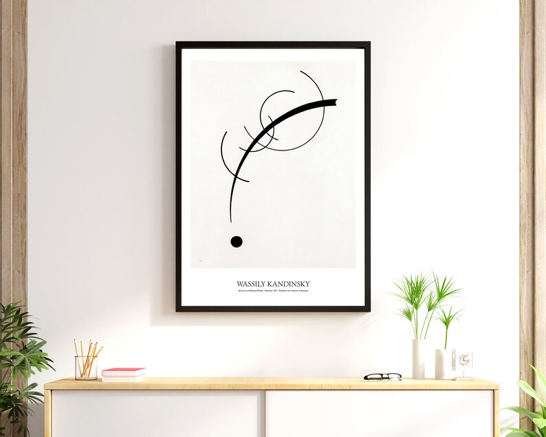 May include: Black and white abstract art print featuring a black curved line and a black circle on a white background. The print is framed in a black frame and has the artist's name, Wassily Kandinsky, printed below the image.