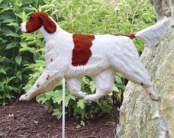 May include: A white and brown wooden figurine of a running Irish Setter dog. The figurine is mounted on a wooden stake for outdoor display.
