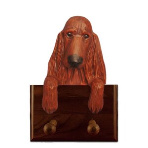 May include: A wooden dog coat rack featuring a carved Irish Setter dog with a brown coat. The rack has two hooks for hanging coats, leashes, or other items.