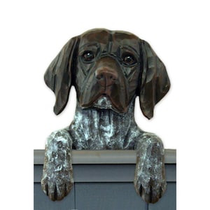 May include: A brown and white German Shorthaired Pointer dog figurine peeking over a ledge. The figurine is made of wood and has a realistic appearance.