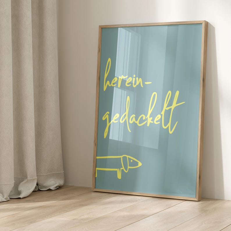 Pode incluir: Uma impress&atilde;o emoldurada com fundo azul claro e texto amarelo que diz "herein-gedackett". Um dachshund amarelo de desenho animado est&aacute; na parte inferior da impress&atilde;o.