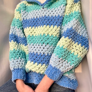 May include: A blue, green, and light blue striped crocheted hooded sweater. The sweater is made with a soft, fuzzy yarn.